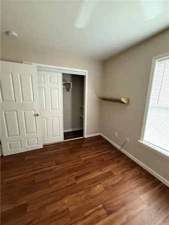 a view of an empty room with wooden floor and window