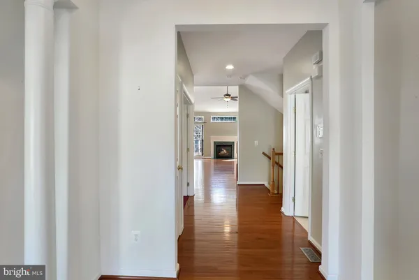 a view of a hallway with wooden floor and a bathroom