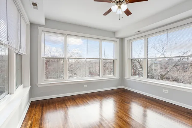 a view of an empty room with a window and wooden floor