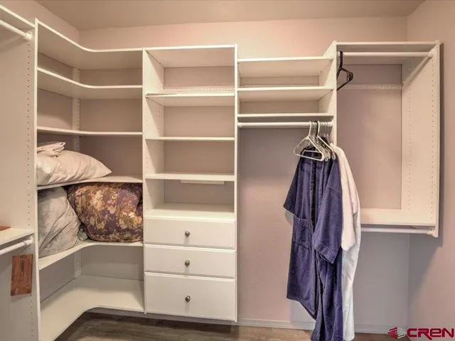 a view of walk in closet with clothes and shoes