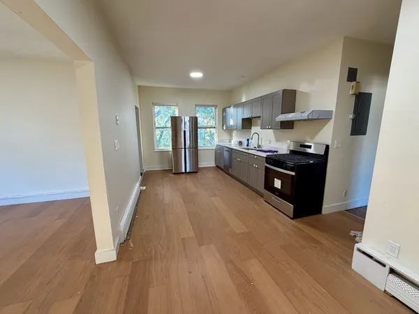 a living room with stainless steel appliances furniture a refrigerator and a view of kitchen