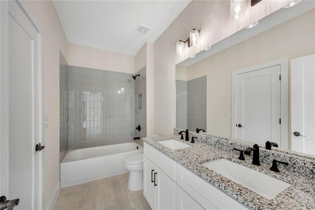 402 Manchester Lane Villa Rica, GA 30180 - Photo 35 of 63 a bathroom with a granite countertop double vanity sink a large mirror and a bathtub