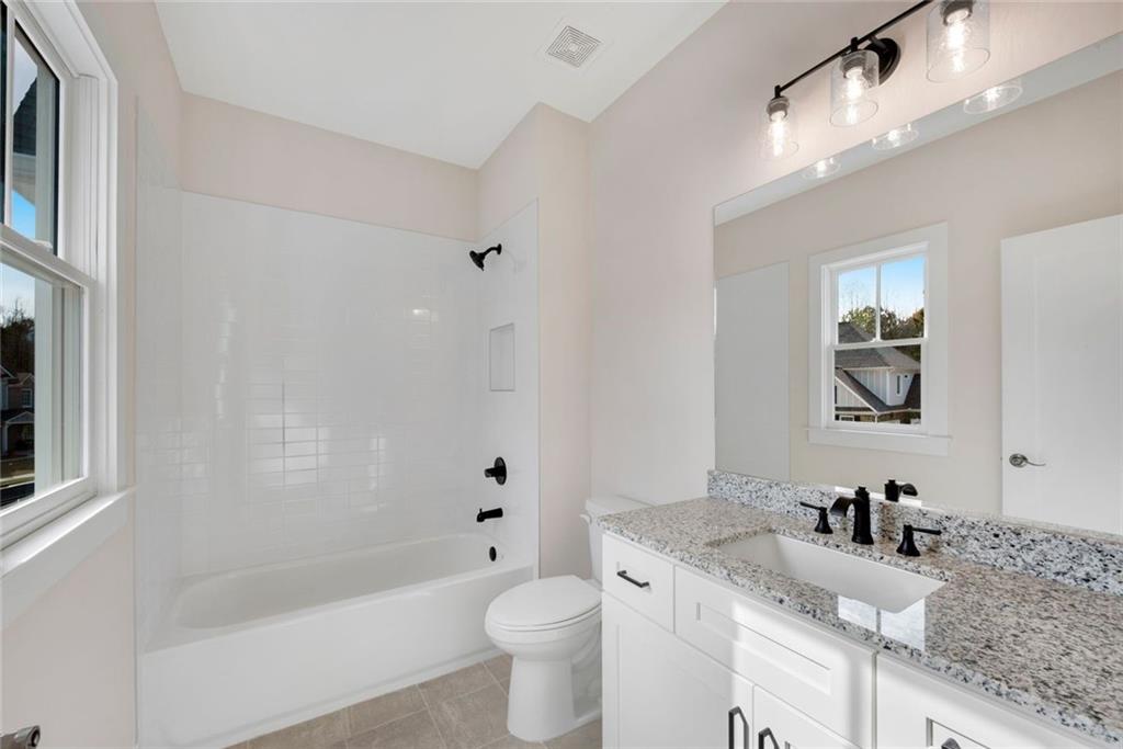 402 Manchester Lane Villa Rica, GA 30180 - Photo 38 of 63 a bathroom with a granite countertop sink a toilet a mirror a bathtub and shower