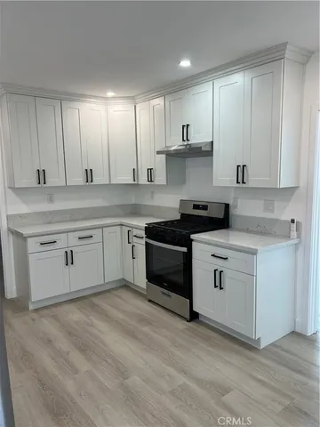 a kitchen with stainless steel appliances granite countertop a stove a sink and white cabinets