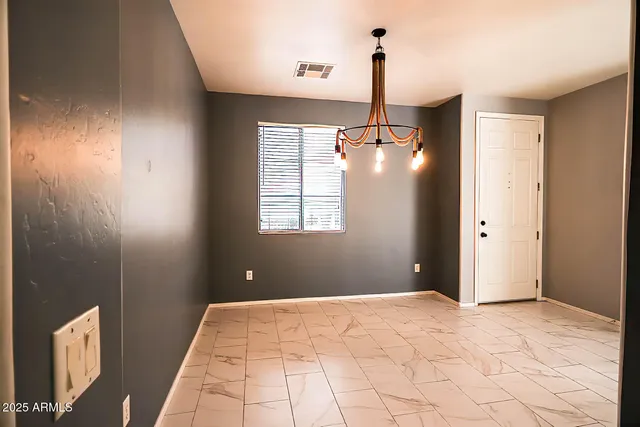 a view of an empty room with window and chandelier fan