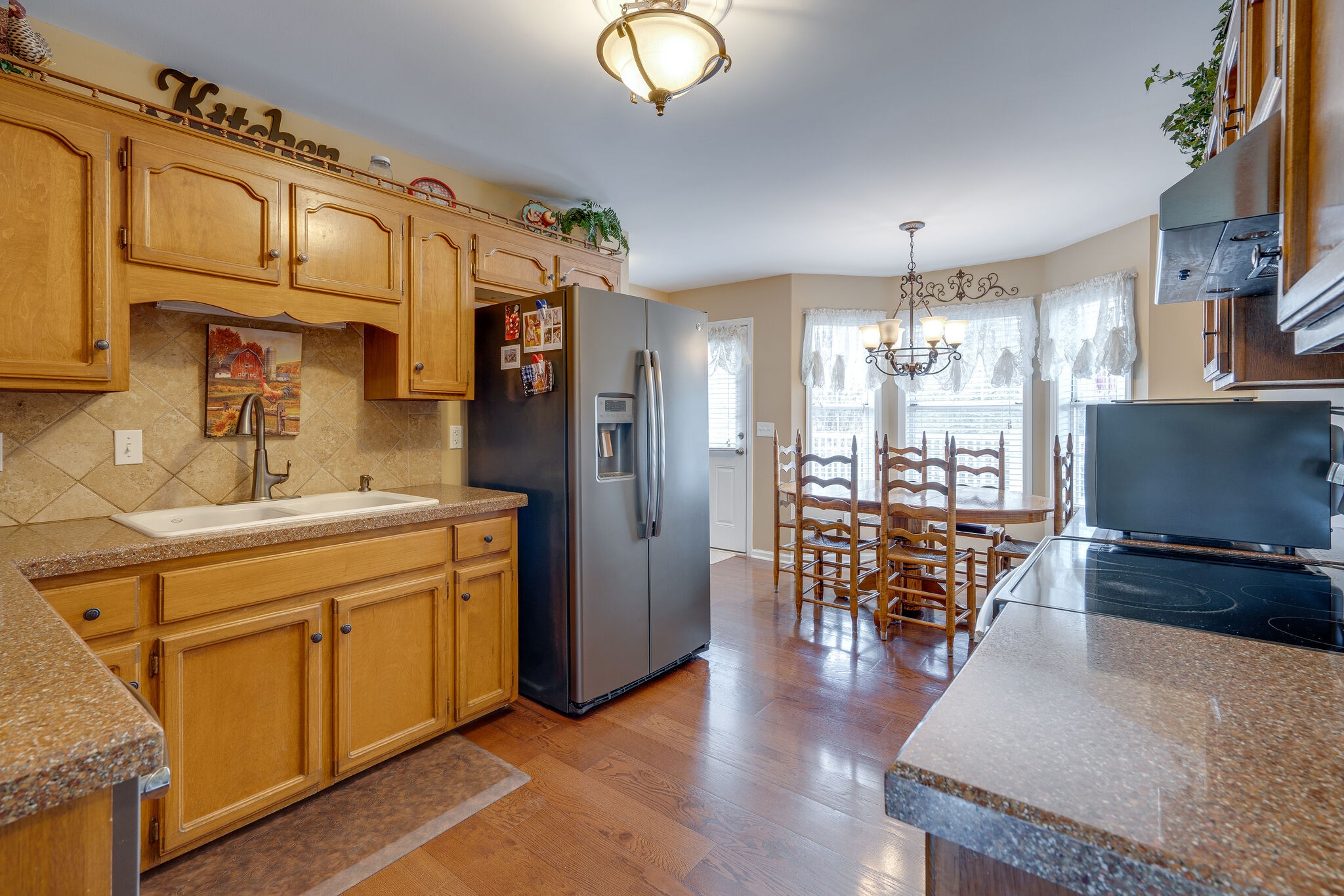 1011 Green Acres Road Joelton, TN 37080 - Photo 11 of 31 a kitchen with stainless steel appliances granite countertop a refrigerator a sink dishwasher a stove and a dining table with wooden floor