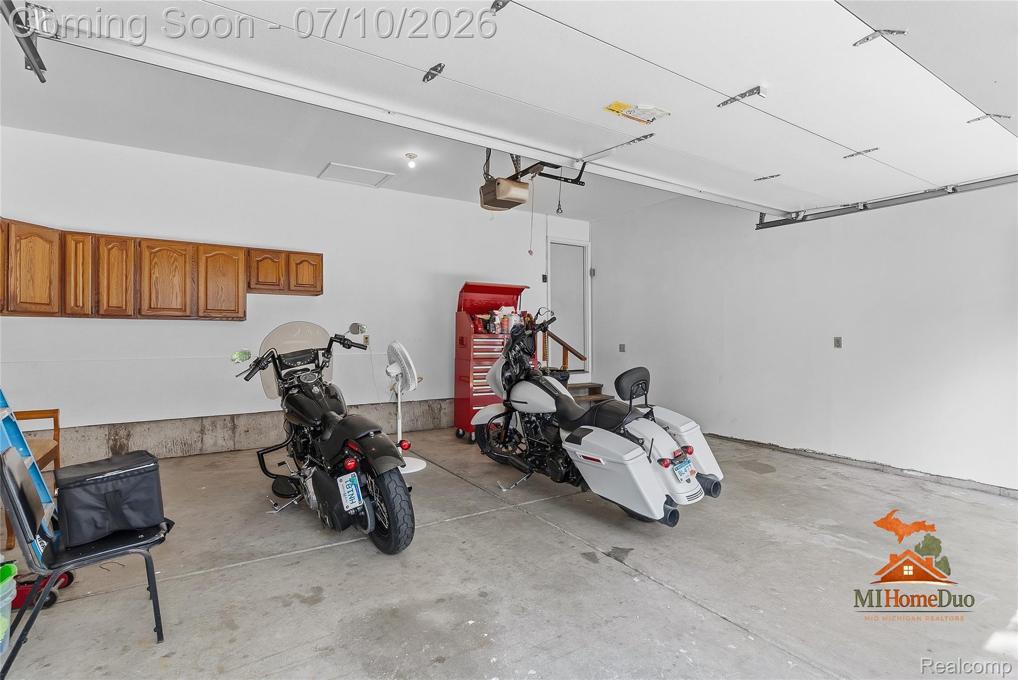 11231 Mcgregor Road Pinckney, MI 48169 - Photo 34 of 37 Spacious garage featuring a concrete floor, overhead garage door track system, recessed lighting, and wall-mounted cabinetry for storage