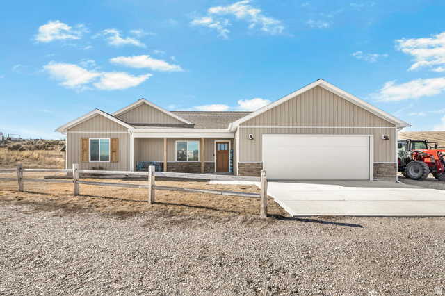 18573 South Marsh Valley Road Downey, ID 83234 - Photo 1 of 32 Ranch-style home featuring concrete driveway, covered porch, stone siding, a garage, and roof with shingles