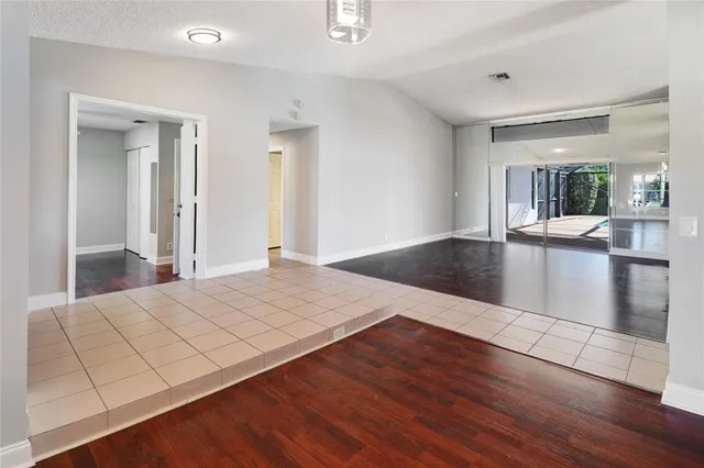an empty room with wooden floor chandelier and windows