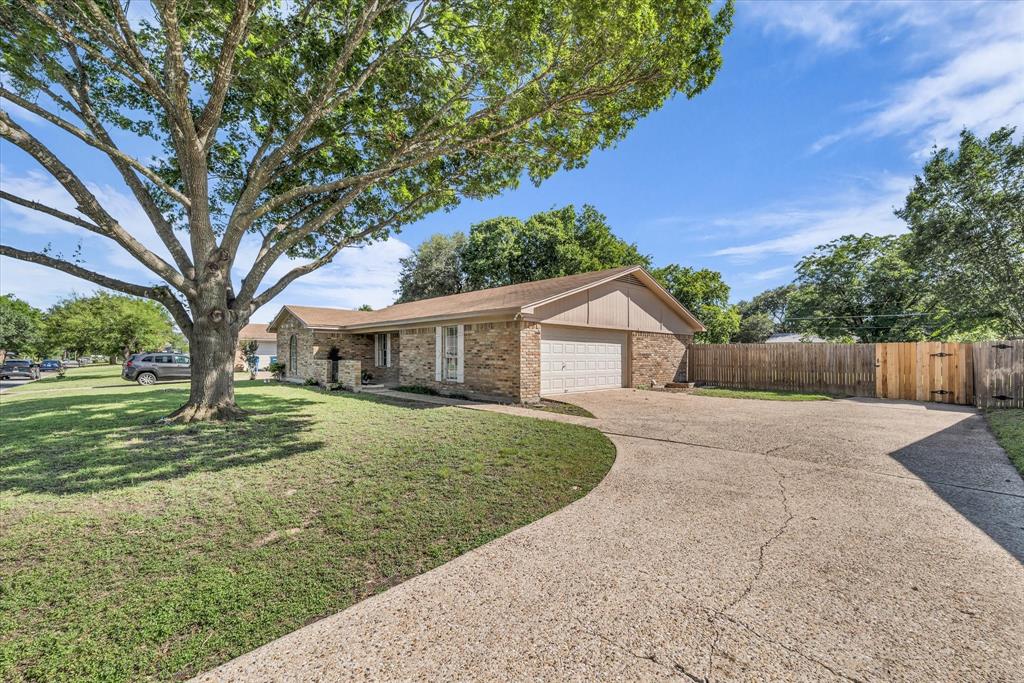 141 Travis Lane Hewitt, TX 76643 - Photo 24 of 31 Brick exterior with an attached garage, a spacious front yard featuring a mature tree, and a concrete driveway leading to a wooden privacy fence