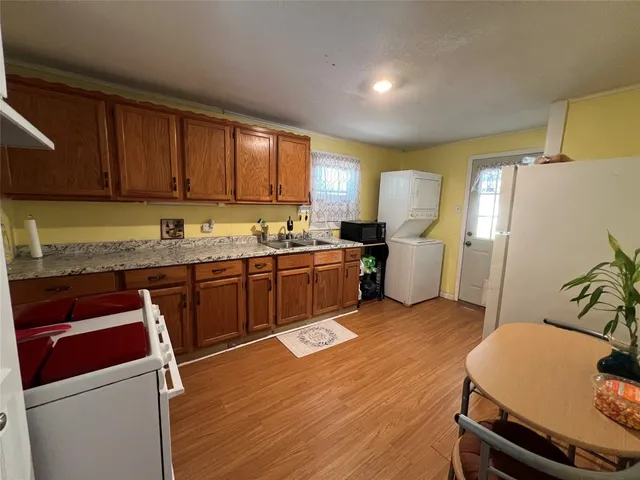 a kitchen with a sink a stove a refrigerator cabinets and wooden floor