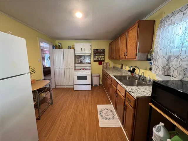 a kitchen with stainless steel appliances granite countertop a refrigerator a sink dishwasher a stove and white countertops with wooden floor