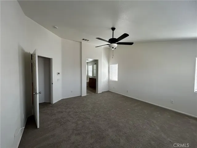 an empty room with chandelier fan and windows