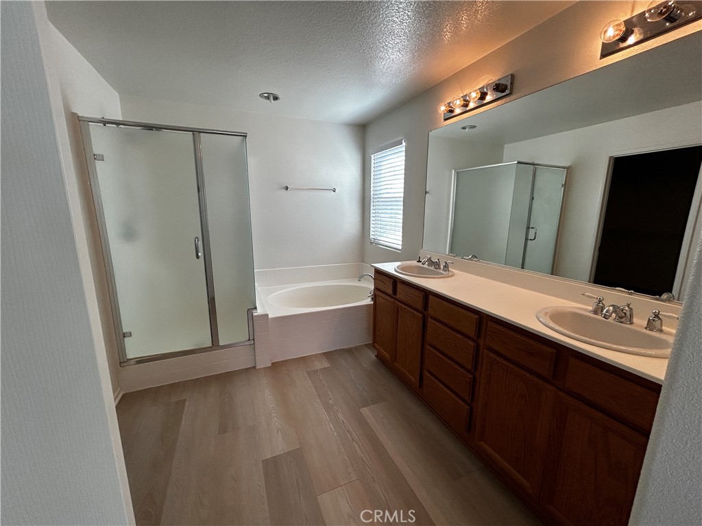 4210 Cloudywing Road Hemet, CA 92545 - Photo 16 of 27 a spacious bathroom with a double vanity sink a large mirror and shower