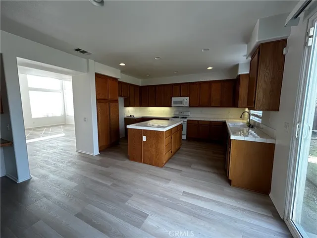 a open kitchen with stainless steel appliances granite countertop a refrigerator a sink a stove and a wooden floors