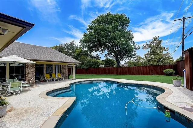 a view of a swimming pool with sitting area in front of house