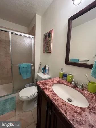 a bathroom with a granite countertop toilet sink and mirror
