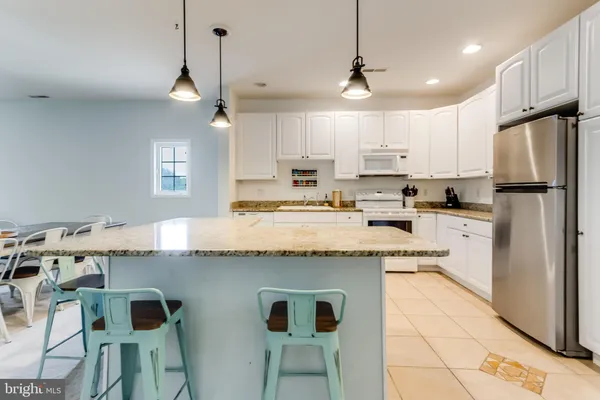 a kitchen with kitchen island granite countertop a sink a center island and appliances
