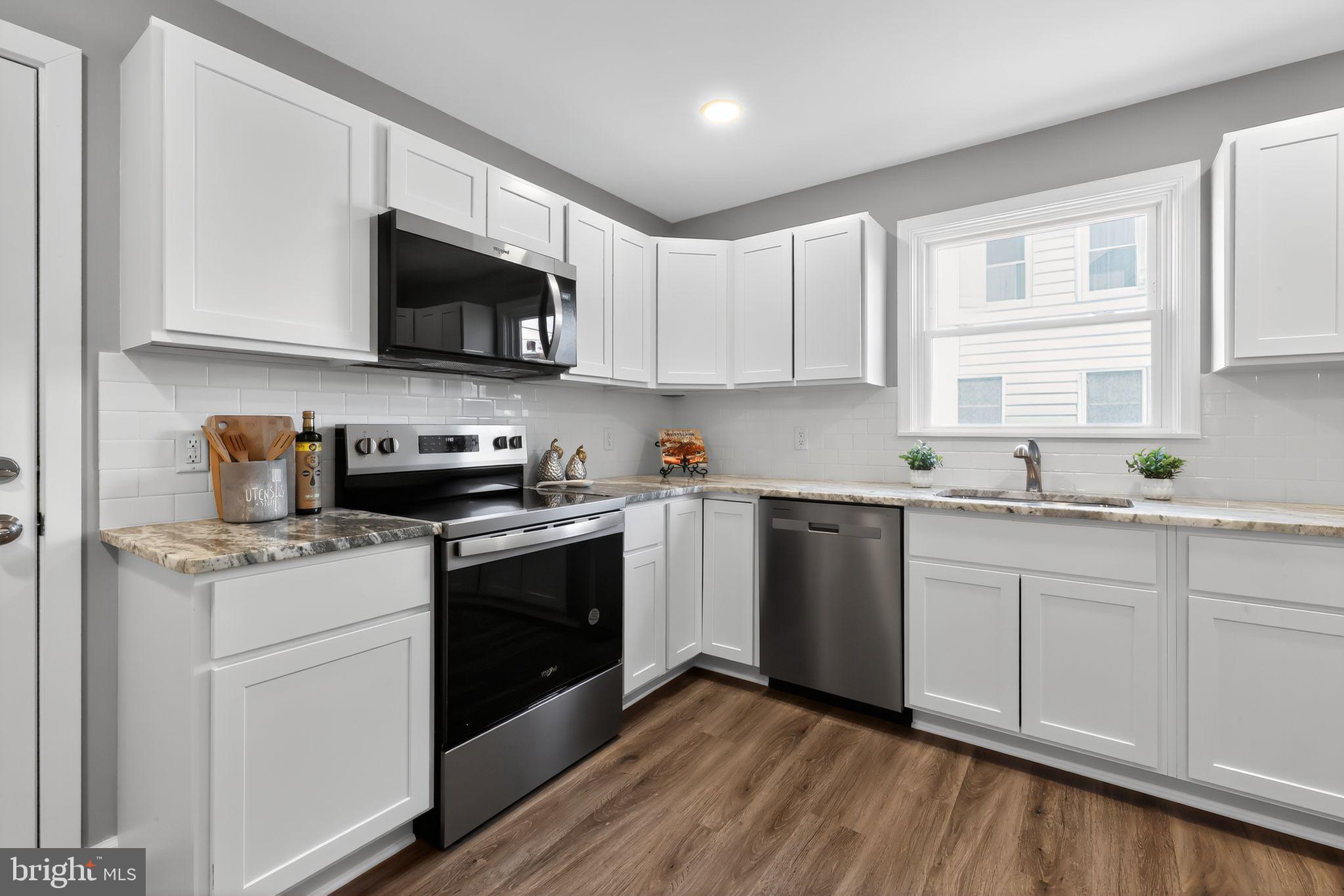 261 West Main Street Elkton, MD 21921 - Photo 12 of 31 a kitchen with stainless steel appliances granite countertop white cabinets a sink a stove a microwave and wooden floors