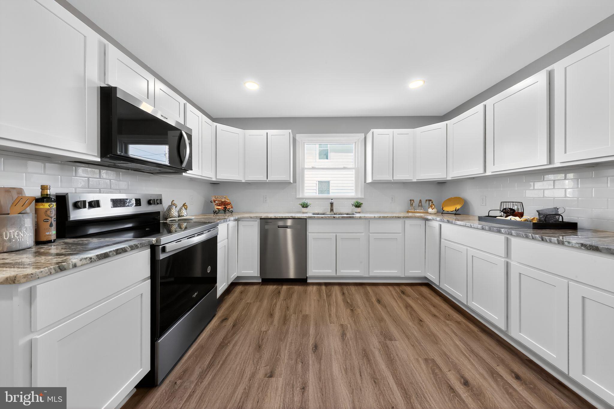 261 West Main Street Elkton, MD 21921 - Photo 4 of 31 a kitchen with stainless steel appliances granite countertop white cabinets a sink a stove a microwave and wooden floors