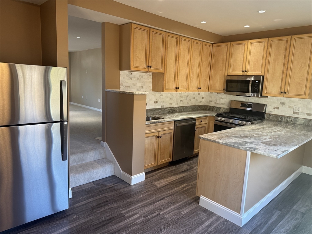 39 Neillian Street, Unit 39 Bedford, MA 01730 - Photo 4 of 29 a kitchen with a sink a microwave a refrigerator and cabinets