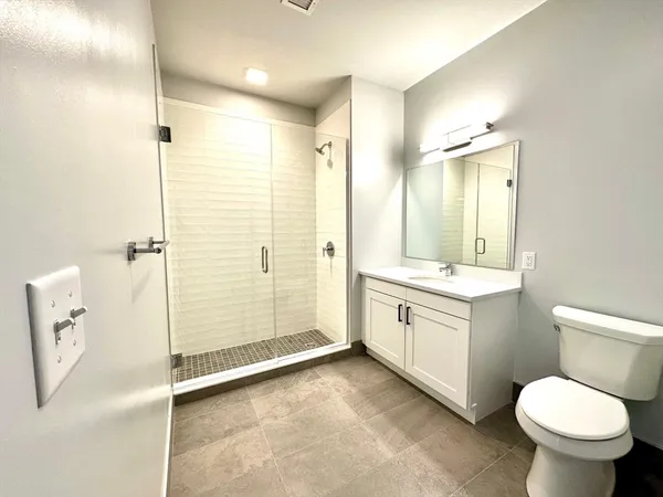 a bathroom with a granite countertop sink a toilet and shower