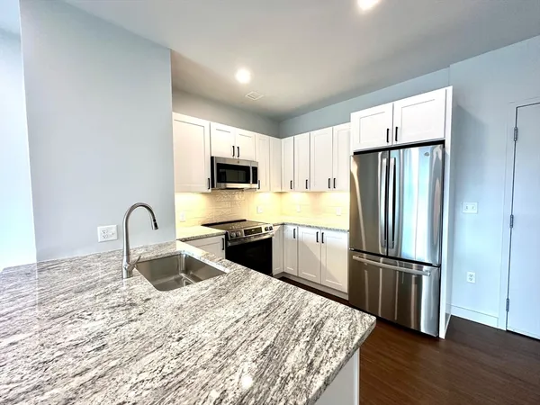 a kitchen with granite countertop a refrigerator and a sink