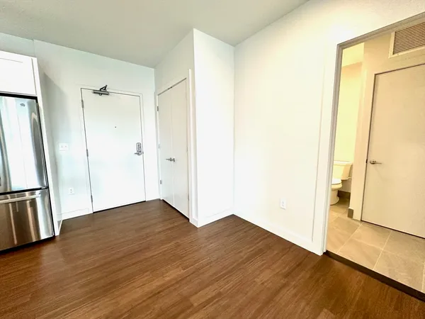 an empty room with wooden floor and a bathroom