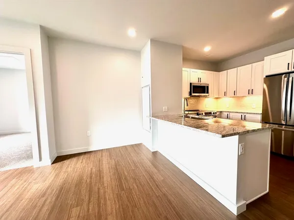 a kitchen with kitchen island wooden floors appliances and cabinets
