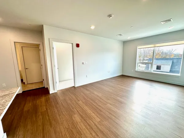 an empty room with wooden floor and windows