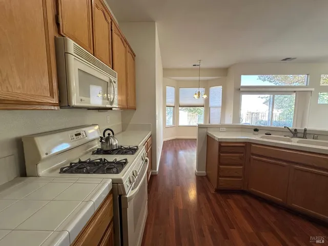 a kitchen with a stove a sink and wooden floor