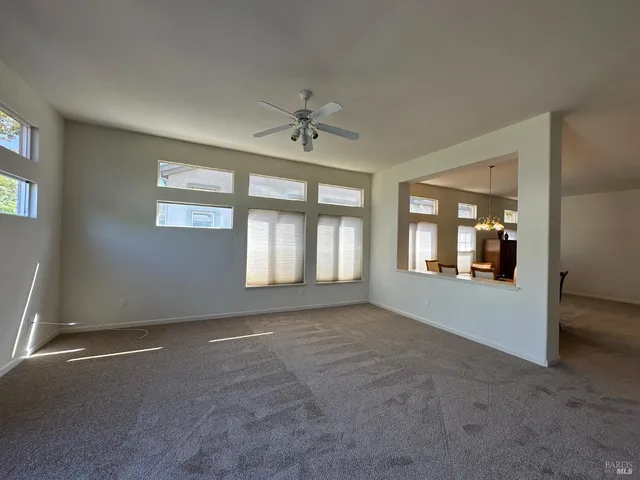 an empty room with windows and ceiling fan