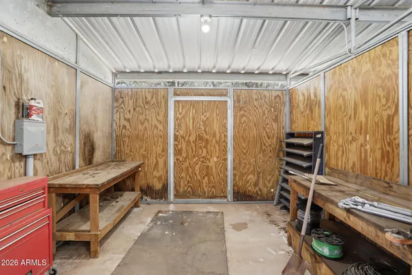 a view of a small white house with large trees and wooden fence