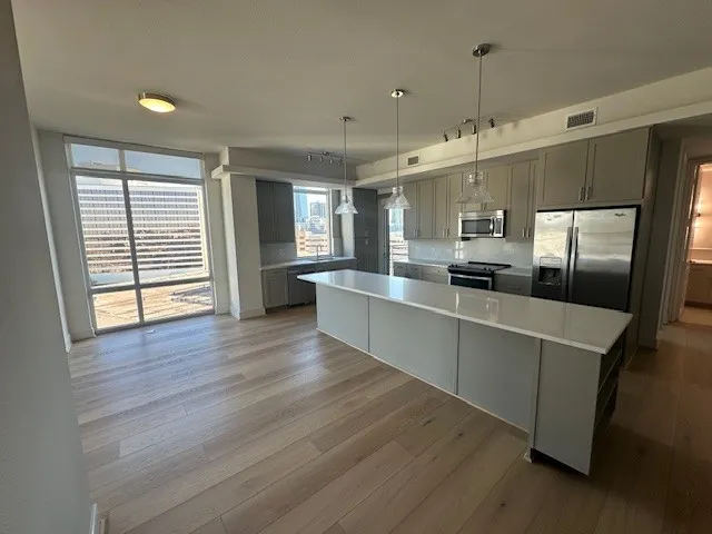 a large kitchen with kitchen island a refrigerator a sink dishwasher a stove and a wooden floors