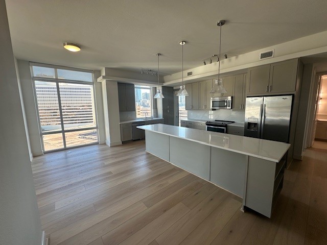 a large kitchen with kitchen island a refrigerator a sink dishwasher a stove and a wooden floors