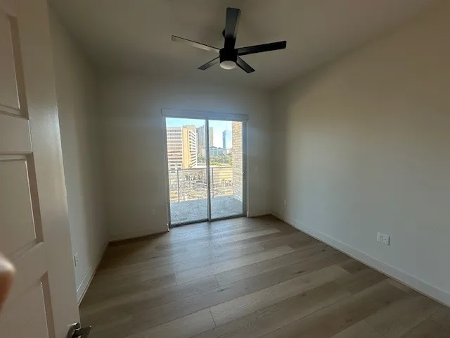 an empty room with wooden floor fan and windows