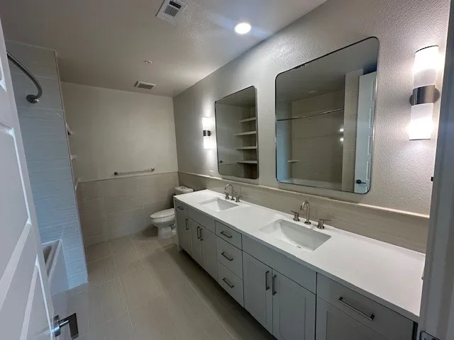 a bathroom with a double vanity sink and mirror with toilet
