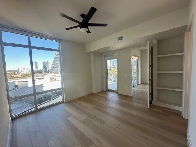 a view of empty room with wooden floor and fan