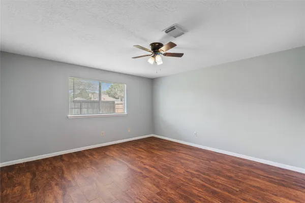 a view of a room with wooden floor and a ceiling fan