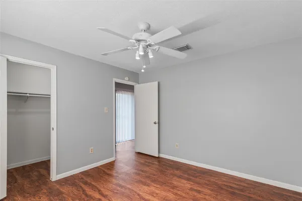 an empty room with wooden floor and ceiling fan