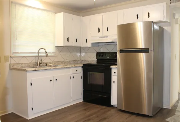 a kitchen with granite countertop a refrigerator sink and cabinets
