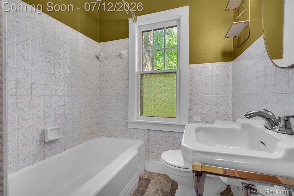 624 North Prospect Road Ypsilanti, MI 48198 - Photo 10 of 28 Bathroom featuring a white porcelain sink with chrome faucet, white bathtub, and white tiled walls