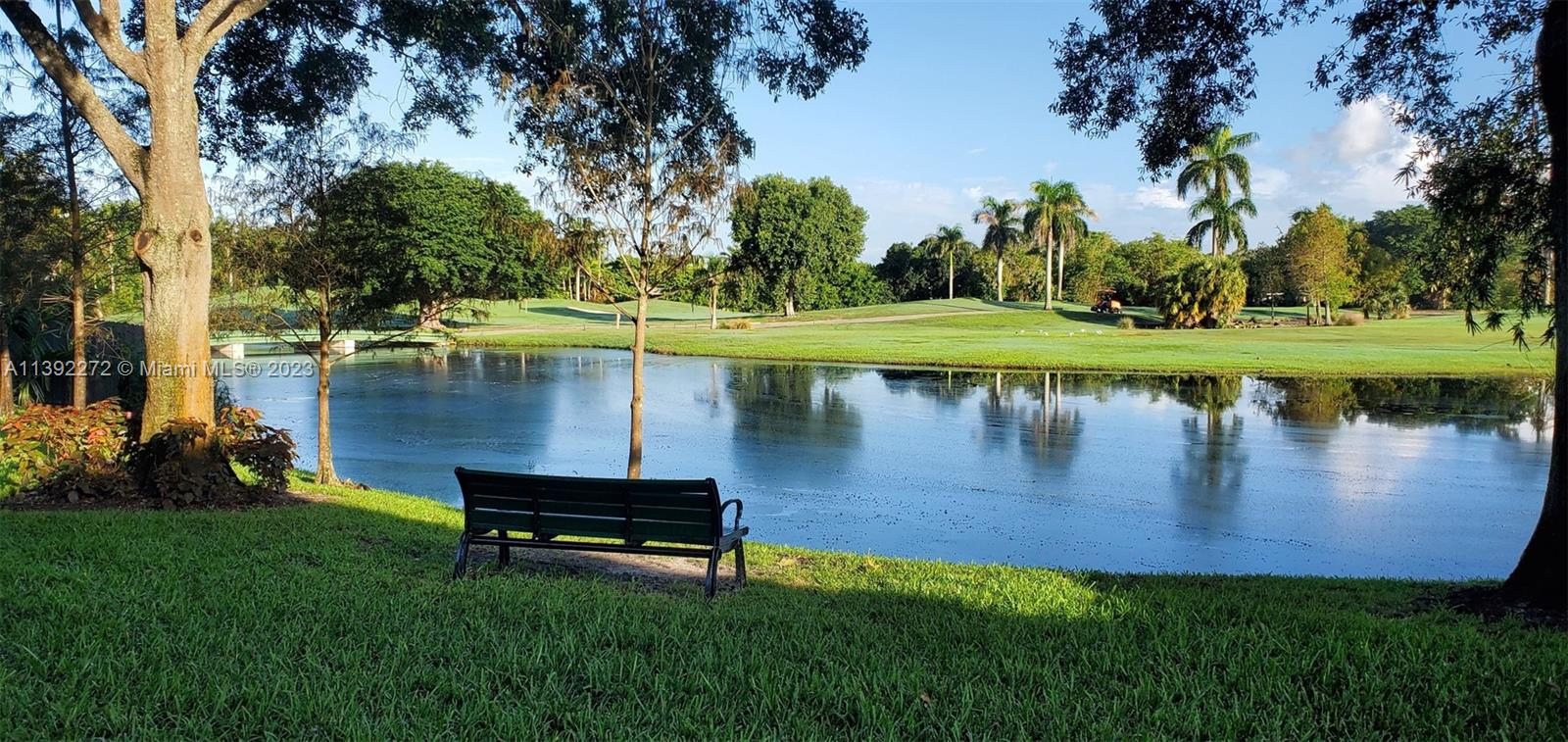 28 Cedar Road Hollywood, FL 33021 - Photo 40 of 43 a view of a lake with a bench and trees