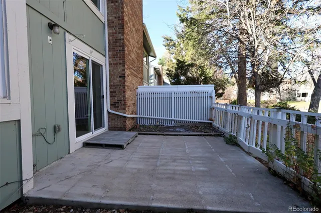 a view of a house with a wooden fence and a large tree