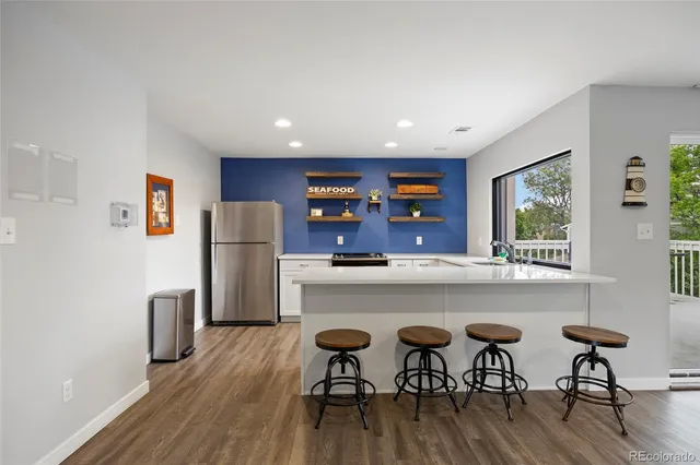 a kitchen with stainless steel appliances a dining table chairs refrigerator and sink