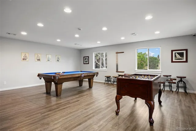 a room with furniture pool table wooden floor and a window