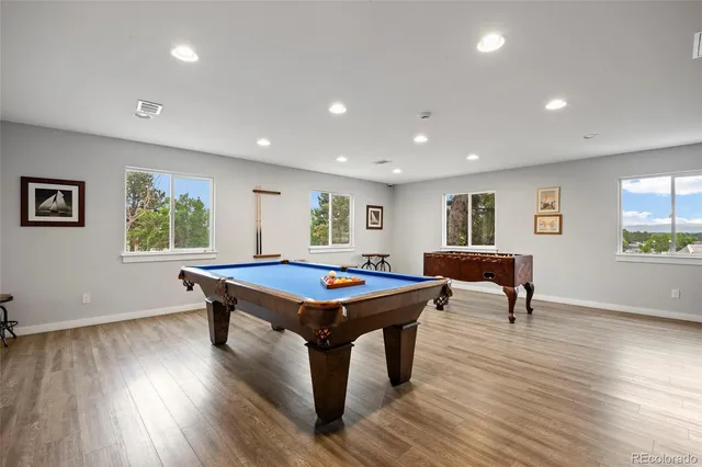 a room with furniture pool table wooden floor and windows