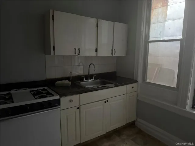 a kitchen with granite countertop a sink stove and cabinets