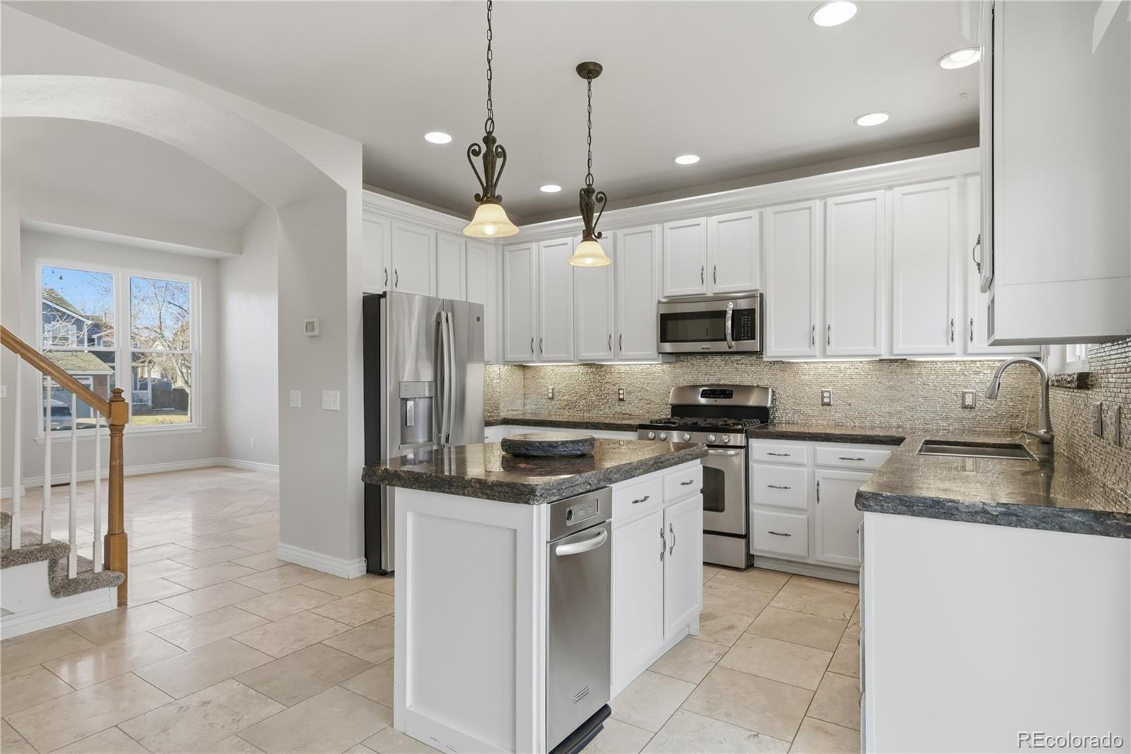 3807 Garnet Way Highlands Ranch, CO 80126 - Photo 11 of 38 a kitchen with stainless steel appliances granite countertop a refrigerator a stove a sink and a microwave
