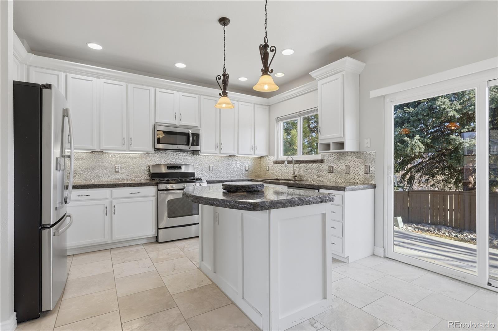 3807 Garnet Way Highlands Ranch, CO 80126 - Photo 12 of 38 a kitchen with granite countertop a sink a counter top space stainless steel appliances and a window